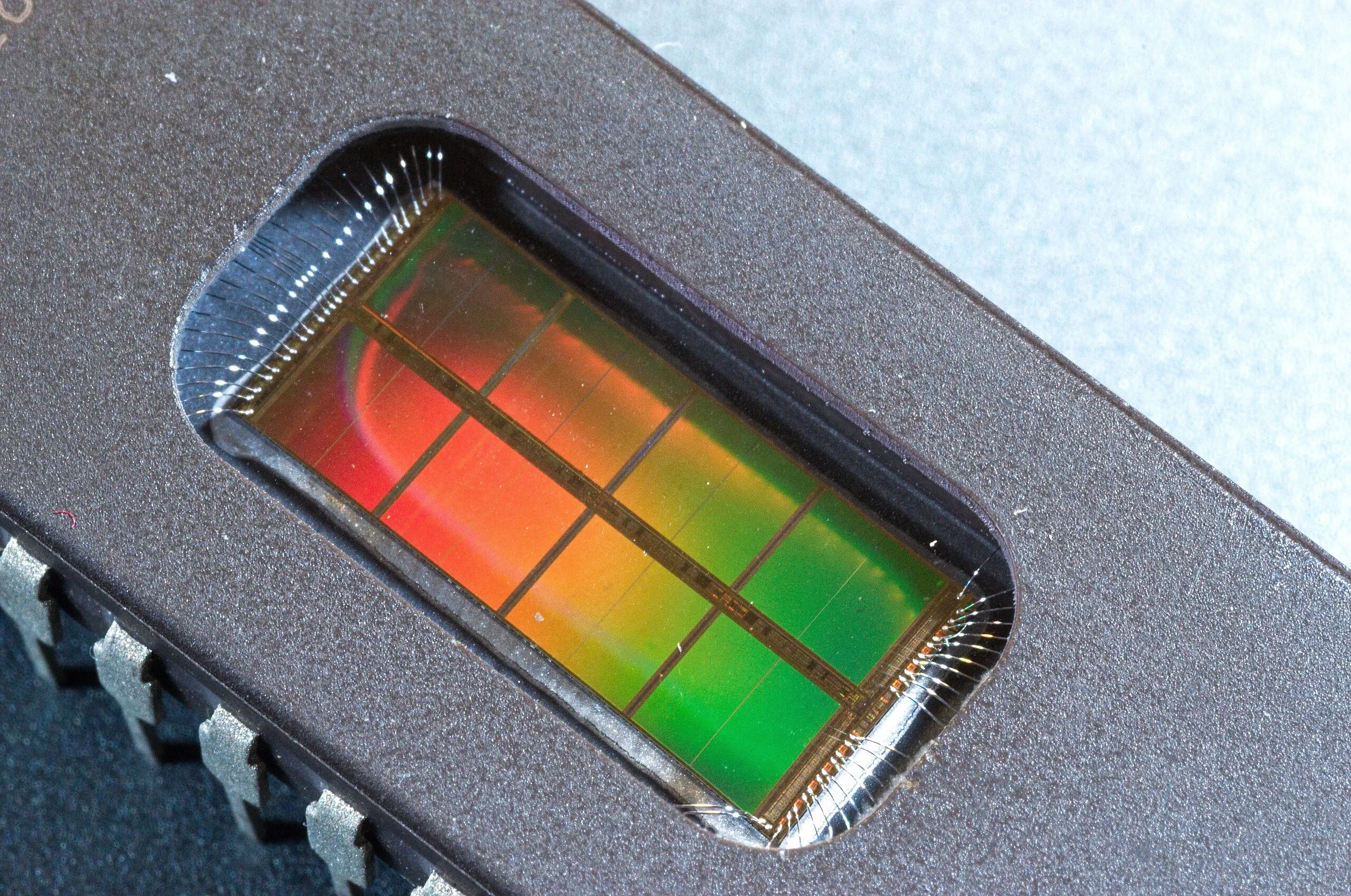 Macro of an EPROM memory chip's quartz window revealing the iridescent silicon die and its fine bond wires