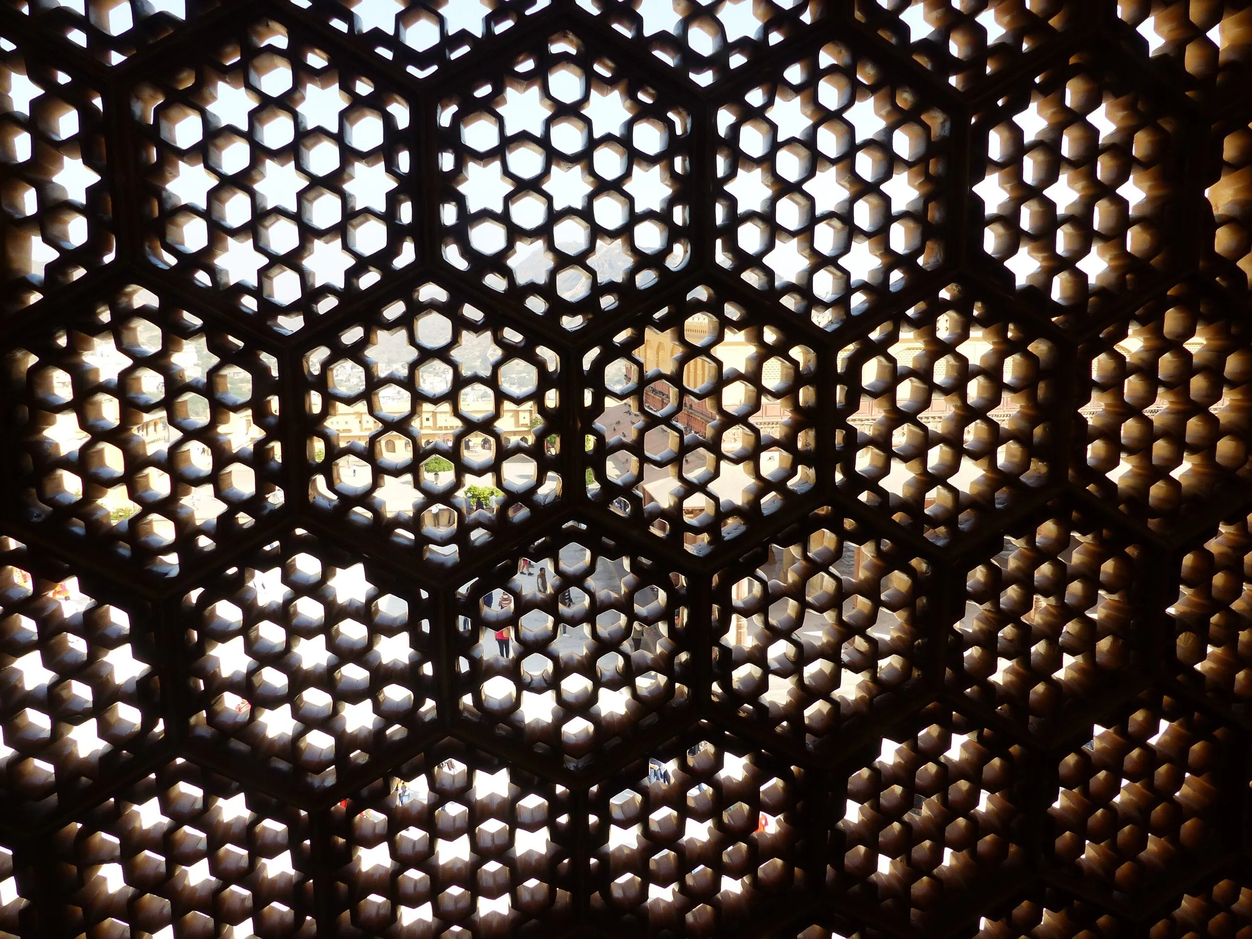 Backlit carved stone jaali screen with star-and-hexagon lattice at Jas Mandir, Amber Fort, Jaipur