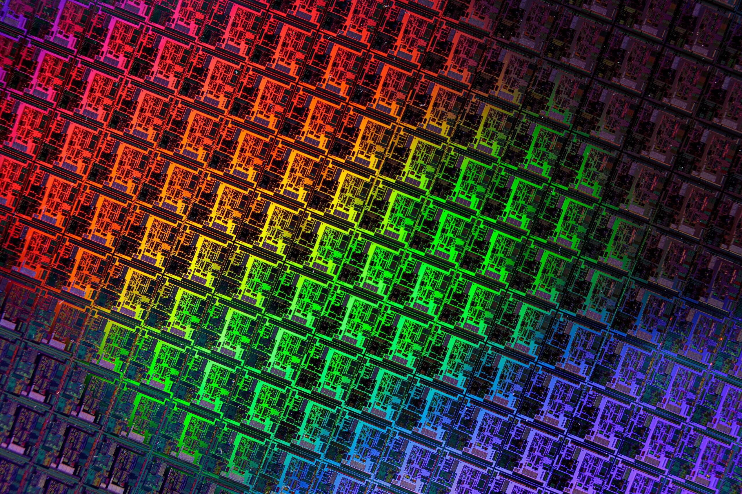 Close view of a patterned silicon wafer, rows of chip dies shimmering in rainbow colour gradients